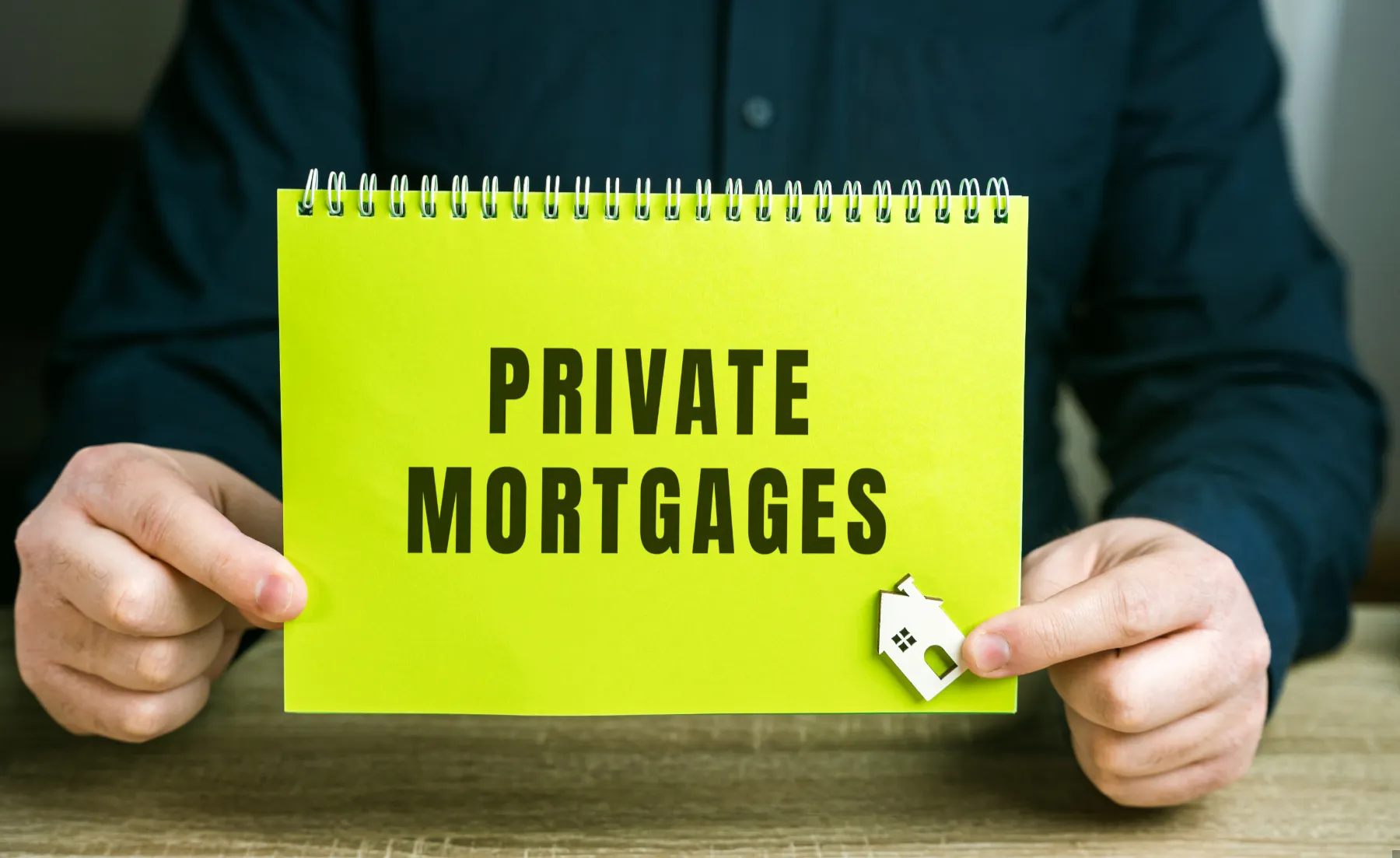 A person holds a yellow-green sign that reads "PRIVATE MORTGAGES" with a small house icon clipped to the corner.