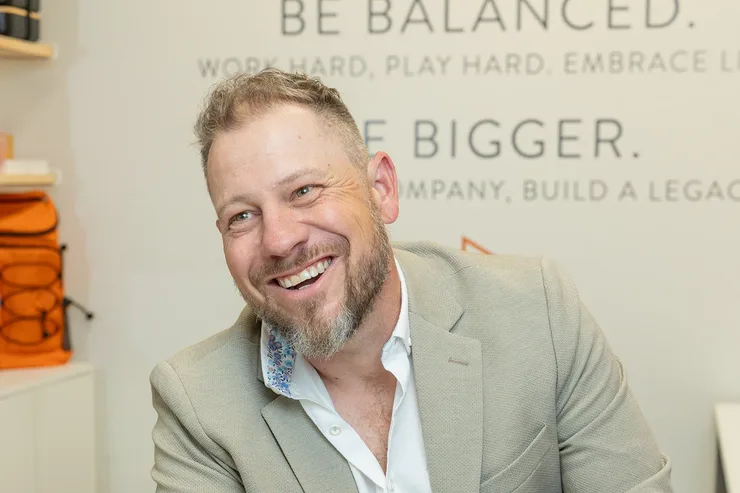 Jordi Browne laughing at his laptop in the Browne Mortgage office