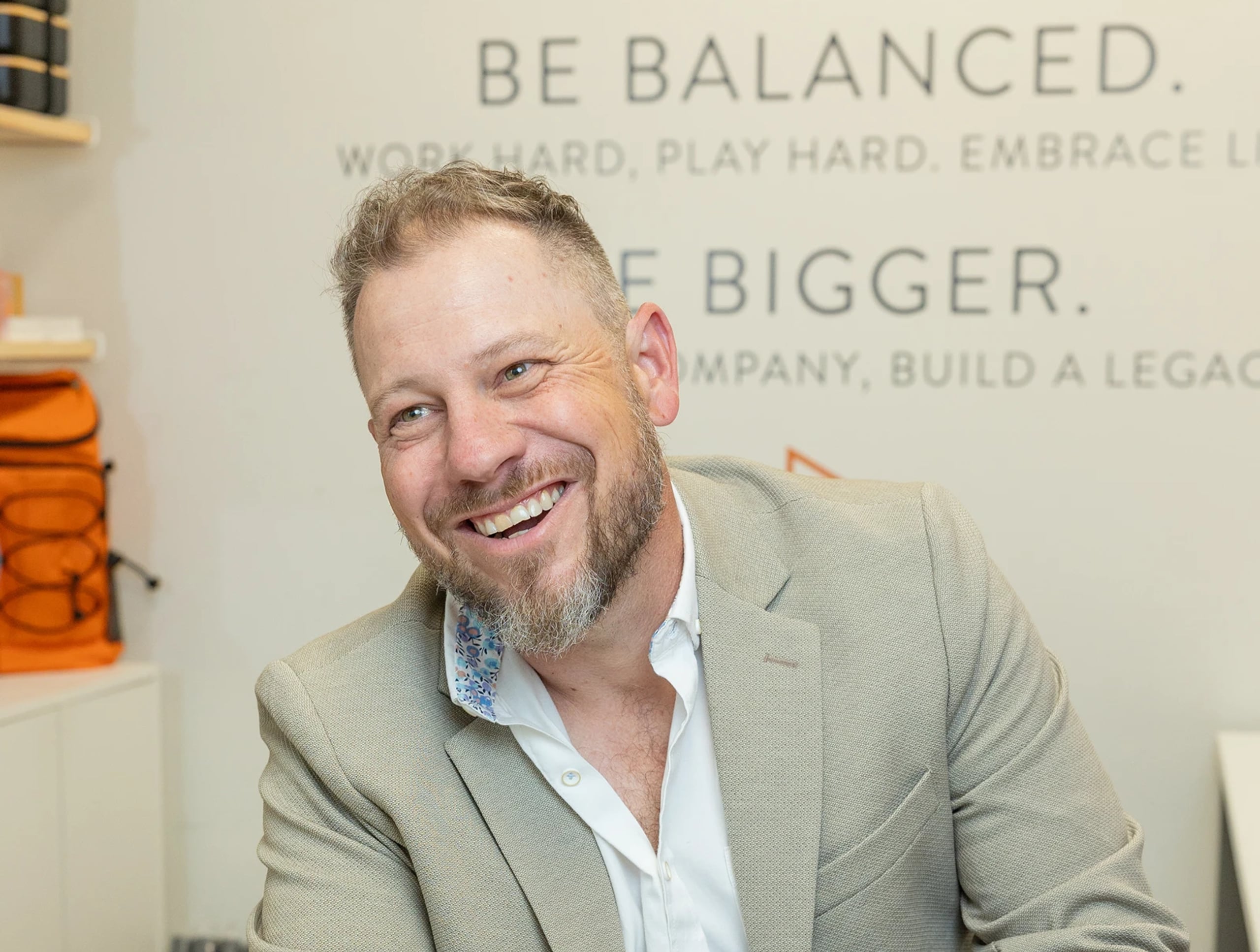 Jordi Browne laughing at his laptop in the Browne Mortgage office